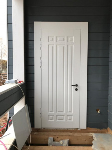 белая входная дверь в деревянном коттедже