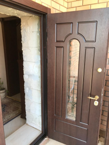 коричневая входная дверь с ковкой и стеклом изнутри