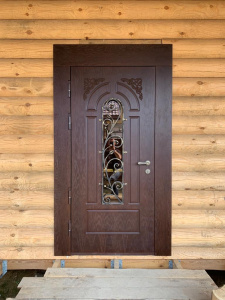 Входная дверь с ковкой и стеклом в деревянном загородном доме
