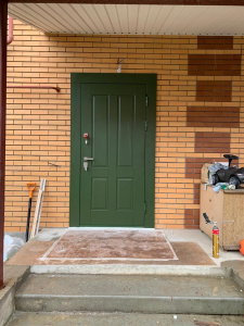 зеленая металлическая двери в кирпичном коттедже