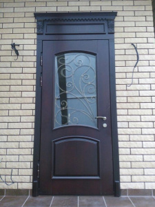 металлическая дверь с ковкой и стеклом в кирпичном доме